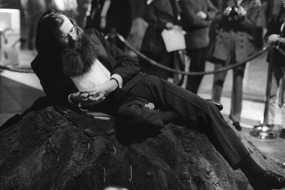 American performance artist and professor Geoffrey Hendricks, dressed in a tuxedo, sits atop a pile of dirt in a silent performance that also involved  a white mouse (on his right leg) at the Eighth Avant Garde Festival at the 69th Regiment Armory (Lexington Avenue at 25th Street), New York,  New York, November 19, 1971. Photo: Fred W. McDarrah/Getty Images.